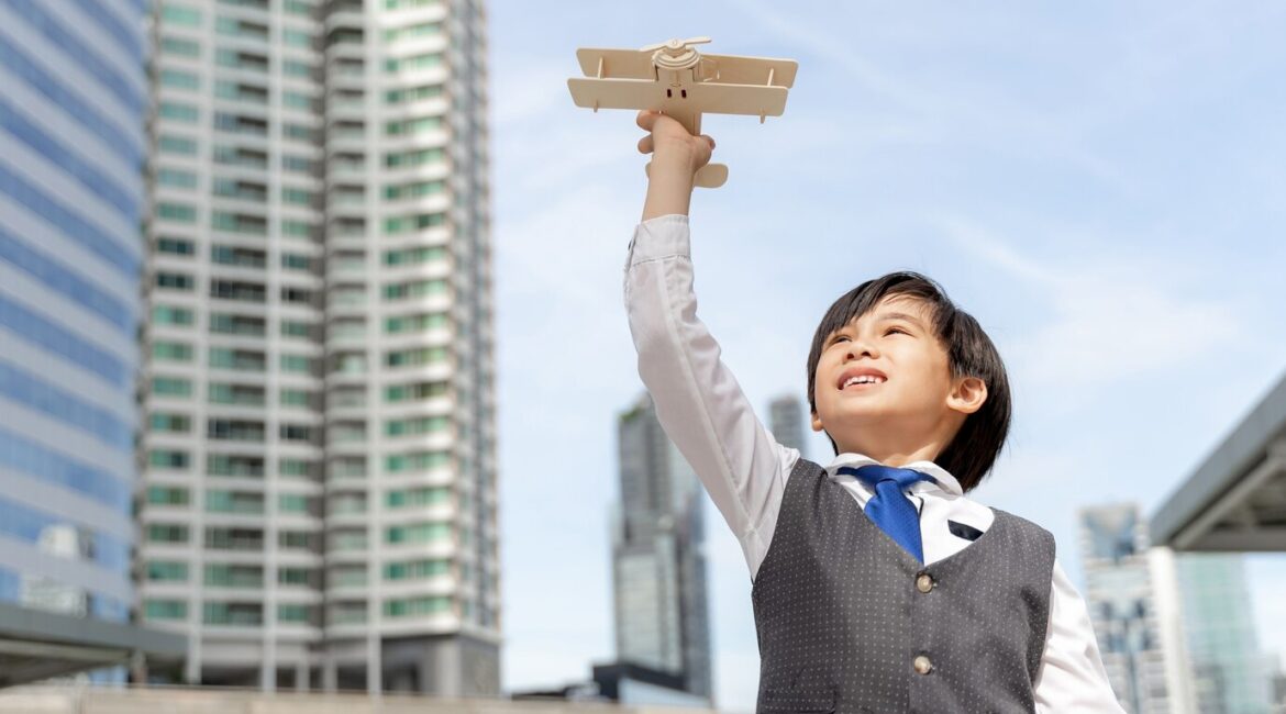 young-boy-playing-aviator-toy-air-plane-imagination-dreaming-being-pilot-future-business-district-urban_1150-34755
