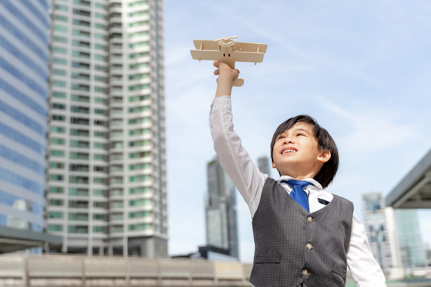 young-boy-playing-aviator-toy-air-plane-imagination-dreaming-being-pilot-future-business-district-urban_1150-34755